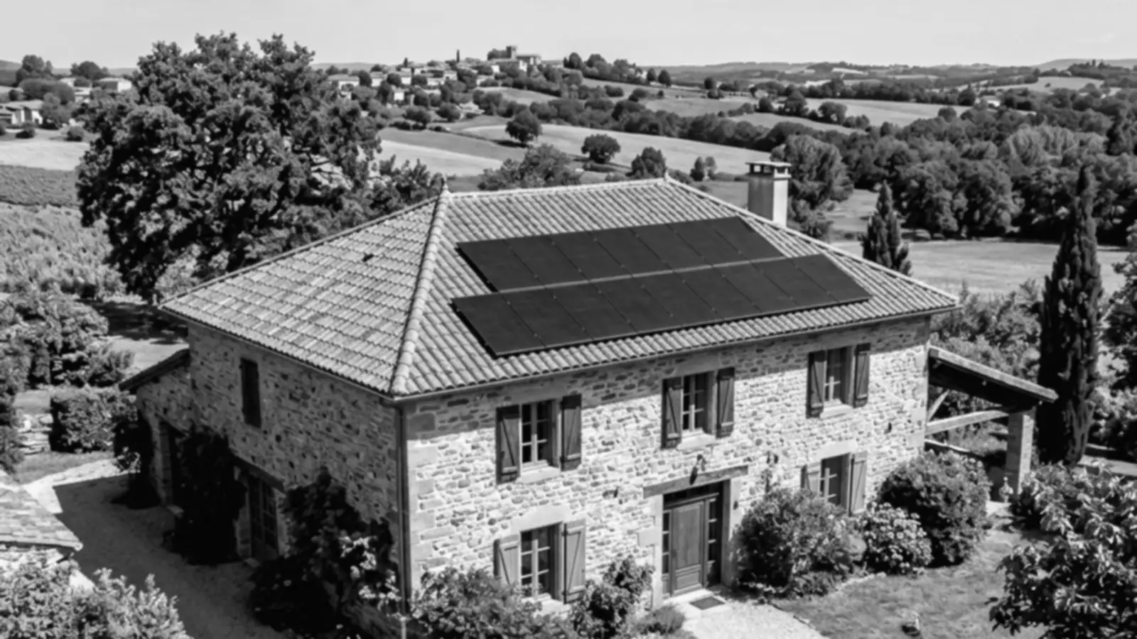 Maison en pierre du Tarn équipée de panneaux photovoltaïques en toiture, dans un paysage de collines et de vignes